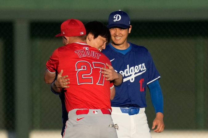 Los Angeles Angels center fielder Mike Trout (27) greets Los Angeles Dodgers designated hitter Shohei Ohtani and his interpreter, Ippei Mizuhara, center, before a spring training baseball game in Phoenix, Tuesday, March 5, 2024. (AP Photo/Ashley Landis)