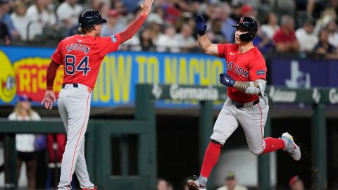 Boston Red Sox Tyler O'Neill is congratulated by third base coach Kyle Hudson (84) as he runs the bases after hitting a solo home run in the fourth inning of a spring training baseball game against the Texas Rangers, Monday, March 25, 2024, in Arlington, Texas. (AP Photo/Sam Hodde)