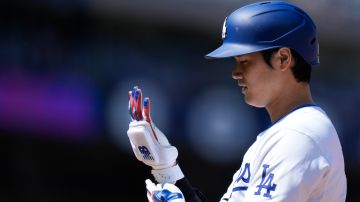 Los Angeles Dodgers' Shohei Ohtani adjust his glove after hitting a single against the St. Louis Cardinals during the fifth inning of a baseball game Thursday, March 28, 2024, in Los Angeles. (AP Photo/Jae C. Hong)