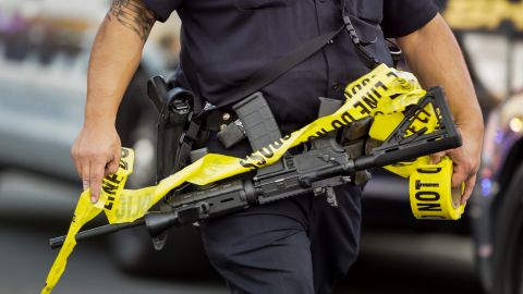 A police officer deploys tape to an area near where authorities stopped a vehicle in San Bernardino, Calif., Wednesday, Dec. 2, 2015. Multiple attackers opened fire on a banquet at a social services center for the disabled in San Bernardino on Wednesday, killing multiple people and sending police on a manhunt for suspects. (AP Photo/Damian Dovarganes)