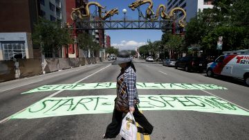 A woman walks past banners protesting against Walmart near the proposed site of a Walmart store in Chinatown on Thursday, Sept. 5, 2013, in Los Angeles. Walmart workers and supporters took part in a nationwide day of protests calling for better jobs and higher wages. (AP Photo/Jae C. Hong)