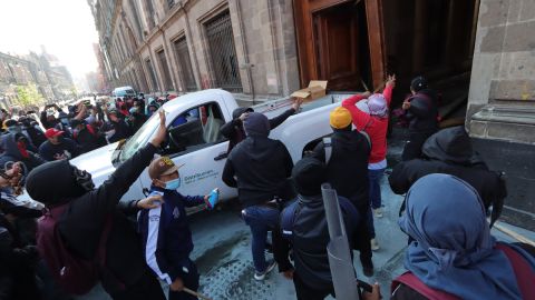 Jóvenes de Ayotzinapa derriban una puerta del Palacio Nacional