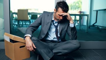 Trabajador de oficina deprimido y en quiebra sentado en el suelo preocupado por el desempleo.