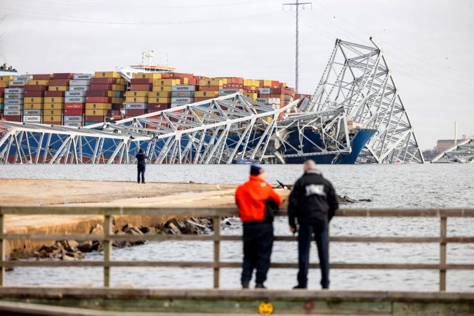 Dos personas viendo el puente Francis Scott Key que se derrumbó parcialmente después de que un buque de carga se topó con él en Baltimore, Maryland, EE.UU.