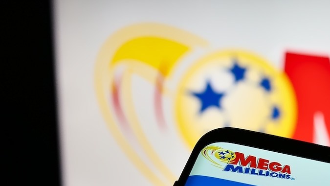 Smartphone con sitio web del juego de lotería estadounidense Mega Millions en la pantalla frente al logotipo