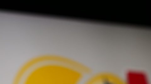 Persona que sostiene el teléfono celular con la página web de la lotería estadounidense Mega Millions en la pantalla frente al logotipo.