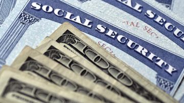 Varias Tarjetas de Seguridad Social y dinero en efectivo que simbolizan la seguridad financiera de las pensiones de jubilación.
