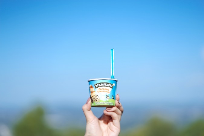 Mano sosteniendo la taza de helado de Ben and Jerry's con sabor a tarta de queso y caramelo