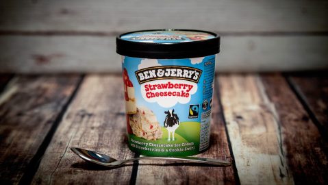 Bote de helado de Ben & Jerry’s sabor tarta de queso y fresa, frente a un fondo de madera.