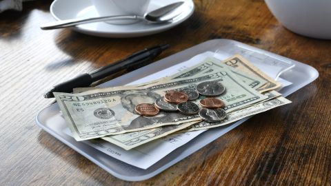 Pagar la cuenta de tu factura en un restaurante con dinero en efectivo.