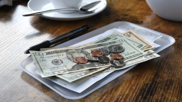 Pagar la cuenta de tu factura en un restaurante con dinero en efectivo.