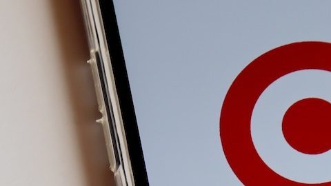 Logotipo de Target en la pantalla del teléfono inteligente y vasos Target y bolsa de compras al fondo