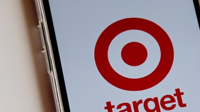 Logotipo de Target en la pantalla del teléfono inteligente y vasos Target y bolsa de compras al fondo