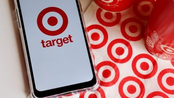 Logotipo de Target en la pantalla del teléfono inteligente y vasos Target y bolsa de compras al fondo
