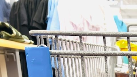 Primer plano de un carrito de compras Walmart entre pasillos.