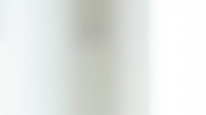 Un adulto mayor se sienta en el sofá de casa y se ríe hablando por un teléfono celular moderno.