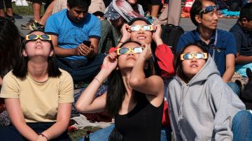 People wearing protective glasses watch the solar eclipse at the Griffith Observatory in Los Angeles Monday, Aug. 21, 2017. (AP Photo/Richard Vogel)