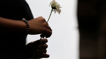 A friend of Carl Angelo Arnaiz, a teenager who was killed in an alleged shootout with police, waits to place a flower on his tomb during a burial ceremony in Manila, Philippines, Tuesday, Sept. 5, 2017. A government forensic team says Carl Angelo Arnaiz, who apparently was handcuffed, was tortured before he was shot five times following an attempted robbery. His death occurred during a renewed police crackdown against drugs and crimes that killed more than 80 suspects in just three days, in the bloodiest few days under Philippine President Rodrigo Duterte's war on drugs. (AP Photo/Aaron Favila)