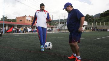 In this photo provided by the Miraflores presidential palace, President Nicolas Maduro, left, kicks the ball with former Argenina soccer great Diego Maradona at the soccer field of the military police academy in Caracas, Venezuela, Tuesday, Nov. 7, 2017. (Miraflores Presidential Palace via AP)