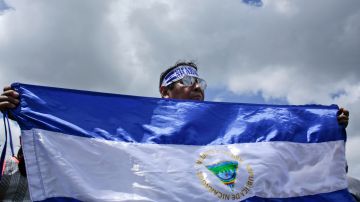 A man holds a Nicaraguan national flag during a demonstration supporting journalists recently attacked while covering protests demanding the resignation of President Daniel Ortega and the release of all political prisoners, in Managua, Nicaragua, Monday, July 30, 2018. (AP Photo/Arnulfo Franco)