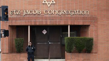 A security guard stands at the entrance of the Etz Jacob Congregation/Ohel Chana High School building Friday, Feb. 15, 2019, in Los Angeles. Police arrested a security guard on suspicion of shooting a self-described First Amendment activist after the two engaged in a videotaped confrontation outside a Los Angeles synagogue and school. (AP Photo/Marcio Jose Sanchez)