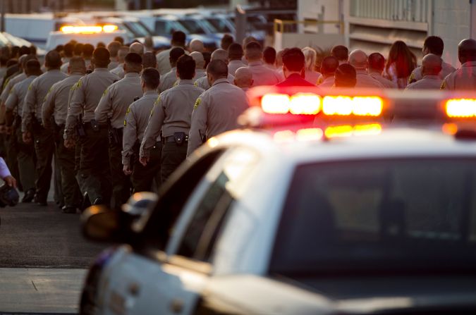 Los Angeles County Sheriff's deputies walk in a procession behind a coroner's van transporting the body of fallen Deputy Joseph Gilbert Solano to the Los Angeles County Department of Medical Examiner-Coroner after a news conference announcing his death, Wednesday, June 12, 2019, in Los Angeles. Solano, who had been on life support, died Wednesday afternoon after being shot in an off-duty attack at a fast-food restaurant on Monday. (AP Photo/Damian Dovarganes)