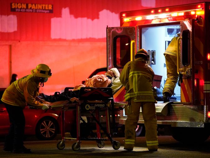 Los Angeles Fire Department paramedics move an injured person into an ambulance after a car crashed against a parked pizza oven trailer on Sunset Boulevard in Los Angeles on Saturday, Dec. 26, 2020. Two people in were transported to a hospital, according to firefighters. (AP Photo/Damian Dovarganes)