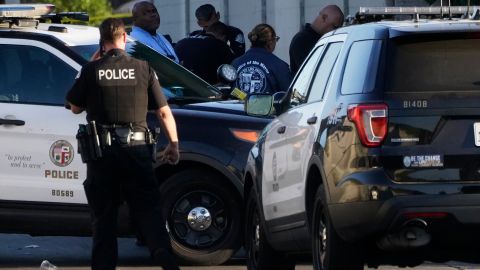 A Los Angeles Police officer and members of the Office of the Mayor of Los Angeles assist witnesses after two people were killed Tuesday, Aug. 2, 2022 in Los Angeles. Authorities say a driver who was fleeing police crashed into a homeless encampment in South Los Angeles, killing a man and a woman. (AP Photo/Damian Dovarganes)