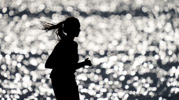 A runner makes her way along the path at Gray's Lake Park, Friday, April 14, 2023, in Des Moines, Iowa. (AP Photo/Charlie Neibergall)