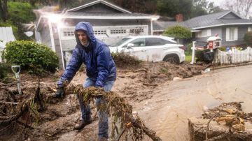Jeffrey Raines clears debris from a mudslide at his parent's home during a rainstorm, Monday, Feb. 5, 2024, in Los Angeles. The second of back-to-back atmospheric rivers took aim at Southern California, unleashing mudslides, flooding roadways and knocking out power as the soggy state braced for another day of heavy rains. (AP Photo/Ethan Swope)