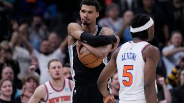 San Antonio Spurs center Victor Wembanyama, center, clutches the ball as they defeat the New York Knicks in an overtime in an NBA basketball game in San Antonio, Friday, March 29, 2024. (AP Photo/Eric Gay)