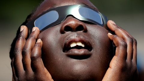 FILE - In this photo taken Friday, Aug. 18, 2017, Poureal Long, a fourth grader at Clardy Elementary School in Kansas City, Mo., practices the proper use of eclipse glasses in anticipation of Monday's solar eclipse. More and more businesses are taking advantage of the total solar eclipse set to dim skies across North America on Monday, April 8, 2024. In the snacks department alone, Krispy Kreme is teaming up with Oreo to sell a limited doughnut-cookie creation. Sonic Drive-In is selling a “Blackout Slush Float.” (AP Photo/Charlie Riedel, File)