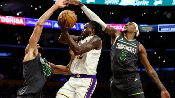Los Angeles Lakers forward Taurean Prince, center, is defended by Minnesota Timberwolves center Rudy Gobert (27) and Minnesota Timberwolves forward Jaden McDaniels (3) during the second half of an NBA basketball game, Sunday, April 7, 2024, in Los Angeles. (AP Photo/Etienne Laurent)