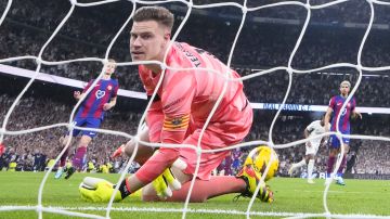 Barcelona's goalkeeper Marc-Andre ter Stegen reacts as he fails to save the ball while Real Madrid's Vinicius Junior celebrates scoring his side's opening goal during the Spanish La Liga soccer match between Real Madrid and Barcelona at the Santiago Bernabeu stadium in Madrid, Spain, Sunday, April 21, 2024. (AP Photo/Manu Fernandez)