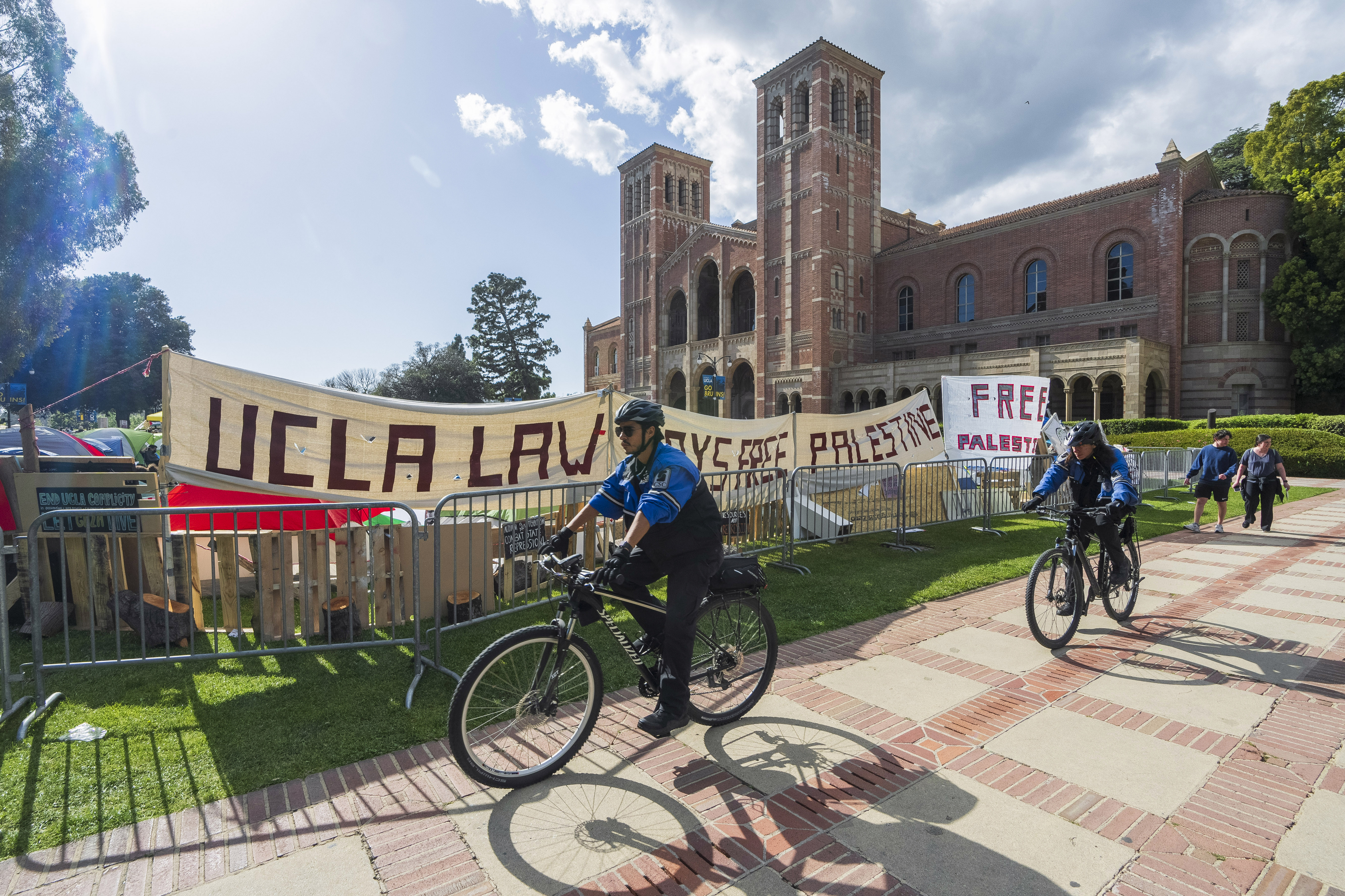 UCLA campus police cycle around the perimeter of a pro-Palestinian encampment on the UCLA campus Friday, April 26, 2024, in Los Angeles. As the death toll mounts in the war in Gaza and the humanitarian crisis worsens, protesters at universities across the country are demanding schools cut financial ties to Israel and divest from companies they say are enabling the conflict. (AP Photo/Damian Dovarganes)