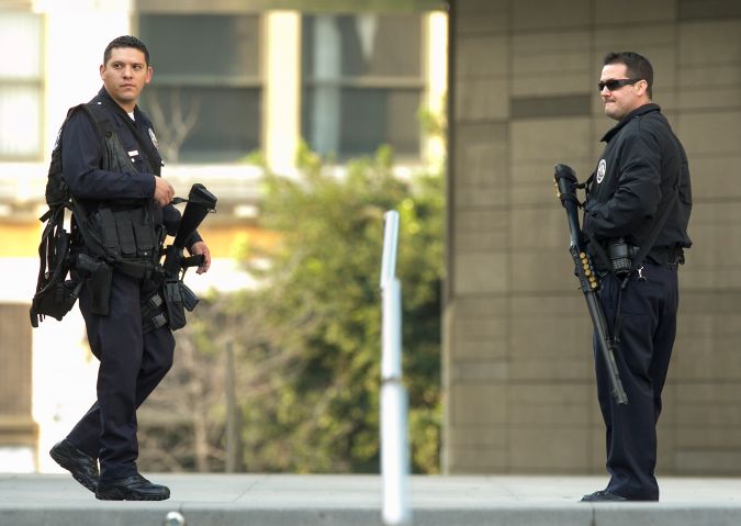 Unidentified police officers guard the Los Angeles Police Department headquarters in Los Angeles Thursday, Feb. 7, 2013. Police launched a massive manhunt for a former Los Angeles officer suspected of going on a killing spree, slaying a couple over the weekend, opening fire on two Los Angeles officers early Thursday and then ambushing two other police officers, killing one. (AP Photo/Damian Dovarganes)