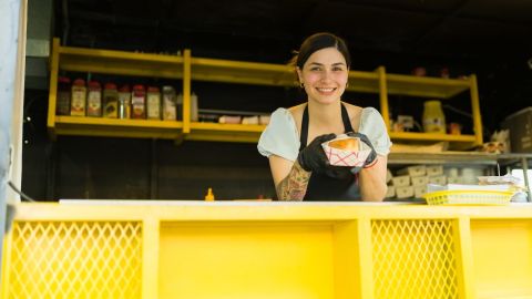Mujer feliz lista para servir comida rápida a los clientes en el camión de comida.