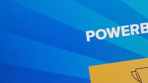 Sitio oficial de Powerball y logotipo en la pantalla de una computadora portátil bajo lupa.