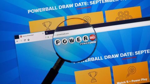 Sitio oficial de Powerball y logotipo en la pantalla de una computadora portátil bajo lupa.