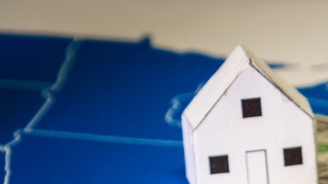 Casas familiares con billetes de dólares e impuestos del gobierno central sobre un mapa de EE.UU.
