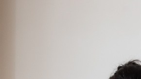 Jovenes en fila frente a una pared blanca revisando sus dispositivos electrónicos.