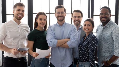 Imagen grupal de jóvenes empresarios multiétnicos felices y diversos posando juntos en el lugar de trabajo en la oficina.