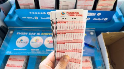 Mano sosteniendo boletos de lotería de Mega Millions.