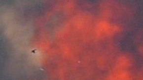A firefighters walks away from a brush fire burning out of control in the Santa Ynez Mountains near Goleta, Calif., on Saturday July 5, 2008. (AP Photo/Phil Klein)