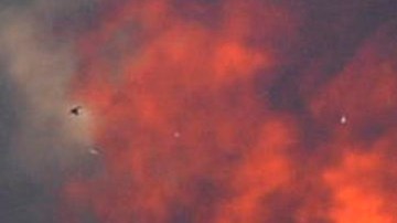 A firefighters walks away from a brush fire burning out of control in the Santa Ynez Mountains near Goleta, Calif., on Saturday July 5, 2008. (AP Photo/Phil Klein)