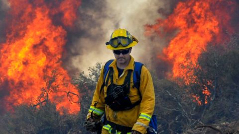 A firefighters walks away from a brush fire burning out of control in the Santa Ynez Mountains near Goleta, Calif., on Saturday July 5, 2008. (AP Photo/Phil Klein)