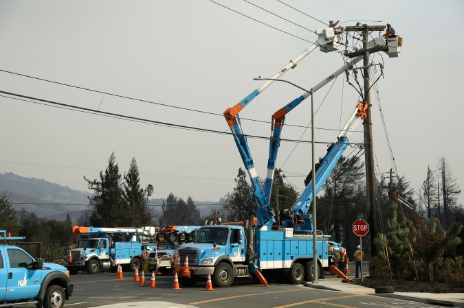 A Pacific Gas and Electric crew works at restoring power along the Old Redwood Highway Wednesday, Oct. 11, 2017, in Santa Rosa, Calif. Officials say they have thousands of firefighters battling 22 blazes burning in Northern California and that more are coming from nearby states. (AP Photo/Eric Risberg)