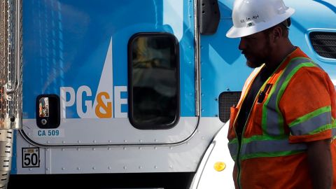 FILE - In this Aug. 15, 2019, file photo, a Pacific Gas & Electric worker walks in front of a truck in San Francisco. Two years to the day after some of the deadliest wildfires tore through Northern California wine country, two of the state's largest utilities were poised Tuesday, Oct. 8, 2019, to shut off power to more than 700,000 customers in 37 counties, in what would be the largest preventive shut-off to date as utilities try to head off wildfires caused by faulty power lines. (AP Photo/Jeff Chiu, File)