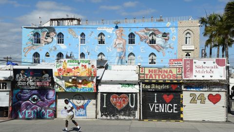 A jogger runs past shuttered shops along Venice Beach Boardwalk, Monday, March 23, 2020, in Los Angeles. Venice Beach Boardwalk was officially closed Monday after widespread ignoring of social distancing over the weekend. (AP Photo/Chris Pizzello)