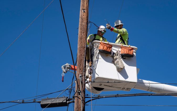 FILE - In this Oct. 25, 2019, file photo, Southern California Edison crews replace power lines that were damaged from the Tick Fire in Santa Clarita, Calif. Southern California Edison announced Sunday, Oct. 25, 2020, on its website it was considering safety outages for 75,000 customers in six Southern California counties. San Bernardino County was expected to be the most affected by those potential cuts. (AP Photo/ Christian Monterrosa, File)